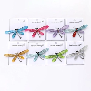Detail view of colorful dragonfly brooches with fiber textured wings and crystal accents