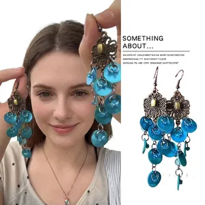 Detail of vintage bronze floral earrings with layered translucent blue charms for women