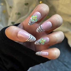 Almond-shaped press-on nails with zebra pattern tips and green floral 3D accents