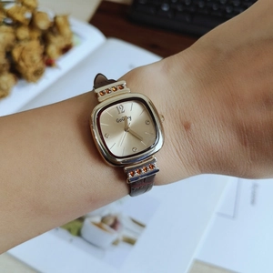 Elegant ladies quartz watch with golden square dial and brown leather strap on wrist