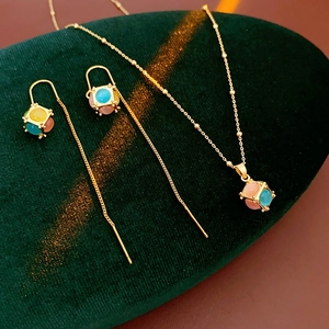 Close-up of gold-plated cube necklaces and earrings with cat-eye stones on velvet