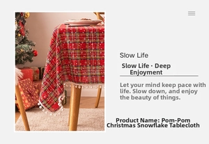 Detail of red plaid Christmas tablecloth with white snowflakes and pom-pom fringe trim
