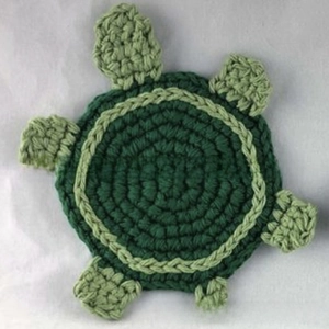 Top view of handmade crochet green turtle coaster showing intricate knitted texture