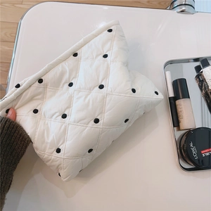 Detailed top view of white quilted lace makeup bag with elegant black polka dot embroidery