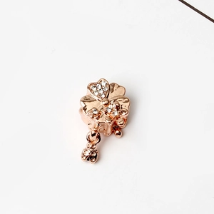 Detail of rose gold four-leaf clover pendant with sparkling rhinestones and heart charm