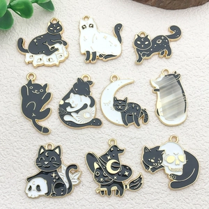 Close-up of 10 assorted black and white enamel cat charms with gold trim for DIY jewelry