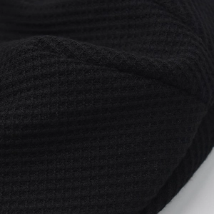 Close-up of black waffle knit fabric showing detailed honeycomb texture and weave