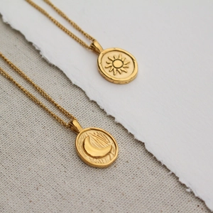18k gold plated stainless steel sun and moon coin necklaces set on beige fabric