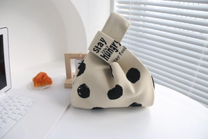 Close-up of knit tote bag with black polka dots and stay hungry lettered handle
