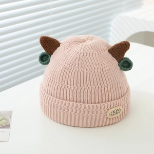 Close-up of pink knit hat featuring cute brown horns and MUM embroidered patch detail