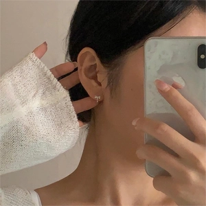 Detail shot of a mini bow-shaped silver stud earring worn on a model earlobe