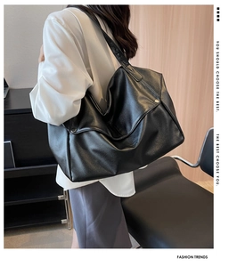 Detail showing the litchi grain texture and side metal buckle of the black tote bag