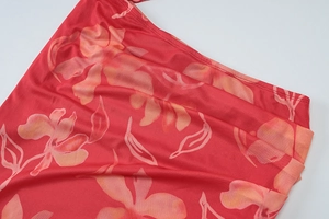 Gros plan sur un tissu en maille rouge avec des motifs floraux orange et rose