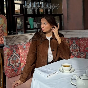 Women's vintage brown faux suede jacket with black buttons in a stylish cafe setting