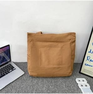 Detail of khaki canvas tote bag with large pocket in a workspace office setting