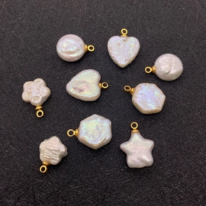 Detailed view of various baroque pearl charms in star and heart shapes on black texture