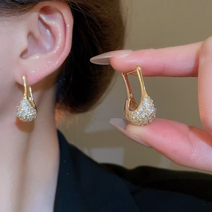 Détail de boucles d'oreilles dorées en forme de U avec pavé de zircons brillants