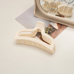 Macro detail of matte cream hair claw clip against a modern minimalist background decor