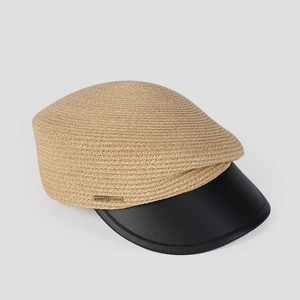 Detail of khaki straw newsboy cap with black leather brim and metallic logo accent