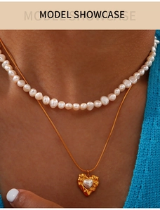 Close-up of double-layer gold necklace with baroque pearls and heart pendant on model