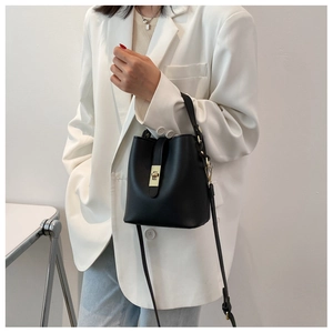 Detail of black PU leather bucket bag featuring a metal clasp and detachable shoulder strap