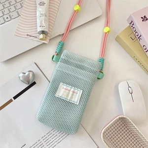 Detail view of a mint green mesh crossbody phone bag with pink cord strap and yellow bead