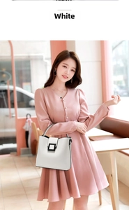 Detail of white lychee pattern handbag with black buckle held by model in pink dress