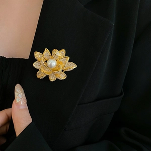 Detailed view of a gold flower brooch with pearls and cubic zirconia on a blazer