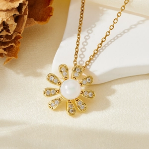 Détail d'un collier fleur doré avec perle et pétales de zircon sur de la soie