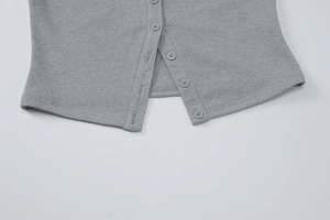 Détail du gilet en maille grise montrant la boutonnière et la texture du tissu