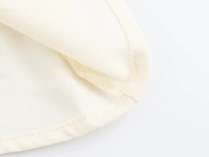 Close-up detail of high-quality woven fabric and precise stitching on the white dress