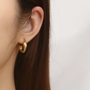 Close-up of a model wearing elegant gold heart-shaped hoop earrings in vintage style