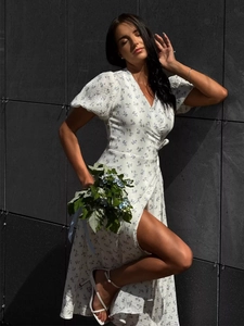 Detailed close-up of white cotton dress with blue floral print and side slit hemline