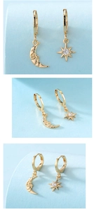 Macro detail of gold asymmetric earrings featuring a crescent moon and zircon star charm