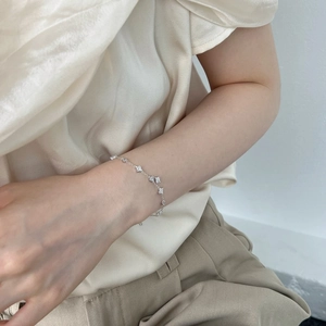 Detail of elegant silver bracelet with small floral charms worn on a woman's wrist