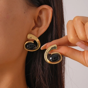 Détail de boucles d'oreilles vintage dorées avec un grand cabochon ovale noir incrusté