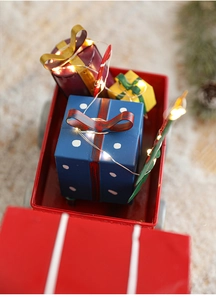 Close-up of red metal Christmas sleigh car with colorful gift boxes and LED lights decoration
