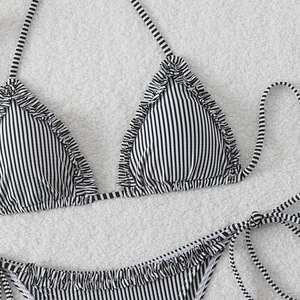 Detailed view of black and white striped bikini with ruffles on soft plush background