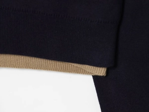 Detail of color-block knit polo shirt showing navy and khaki ribbed cuffs and texture