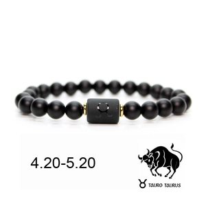 Detail of matte black Taurus zodiac bracelet with gold bead and 4.20-5.20 date range