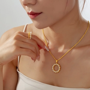 Elegant gold pearl necklace and ring set shown on a model in a minimalist style