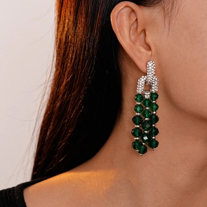 Close-up of long green crystal tassel earrings with silver rhinestones on a model