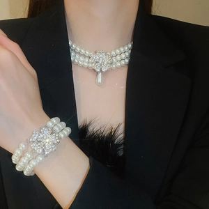 Detail view of the multi-row pearl necklace and bracelet set with diamond flower charms