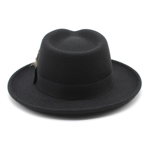Close-up of black wool fedora with ribbon band and feather detail against a white background