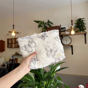 Detail of white lace butterfly cosmetic bag with fringe edges and Sparkle label