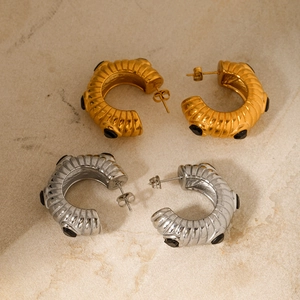 Detail of C-shaped 8K gold stainless steel earrings with black stones and ribbed texture