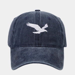 Détail de la broderie d'oiseau blanc sur casquette de baseball en denim délavé