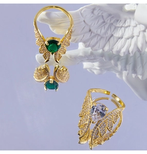 Detailed shot of angel wing rings with green and white pear-cut zircon on purple mirror