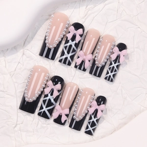 Black and pink press-on nails with 3D bows and pearl accents in long coffin shape