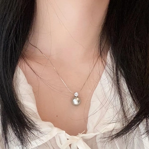 Minimalist stainless steel necklace featuring a 10mm grey pearl pendant worn by a model